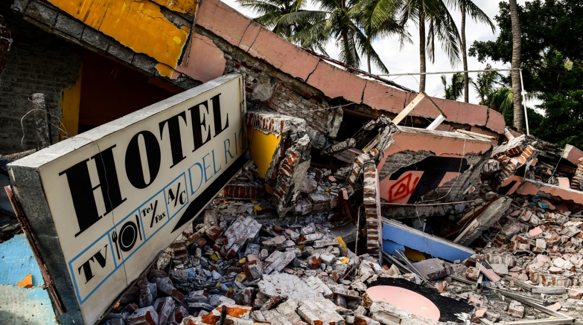 View of a collapsed hotel in Juchitan de Zaragoza, state of Oaxaca on September 10, 2017, following the 8.2 magnitude earthquake that hit Mexico's Pacific Coast on September 8.
Mexican families picked nervously at the ruins of their homes Sunday as help trickled in after a huge earthquake killed 90 people. People in Juchitan were afraid to return to their homes, fearing the effects of hundreds of aftershocks -- but camped within sight of them to prevent looting. / AFP PHOTO / RONALDO SCHEMIDT
      Caption