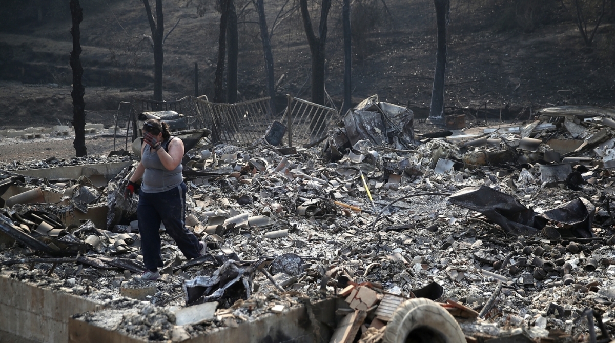 NAPA, CA - OCTOBER 13: Heather Tiffee wipes her eyes as she looks through the remains of her parents' home after it was destroyed by the Atlas Fire on October 13, 2017 in Napa, California. At least thirty one people have died in wildfires that have burned tens of thousands of acres and destroyed over 3,500 homes and businesses in several Northern California counties. Justin Sullivan/Getty Images/AFP
Caption