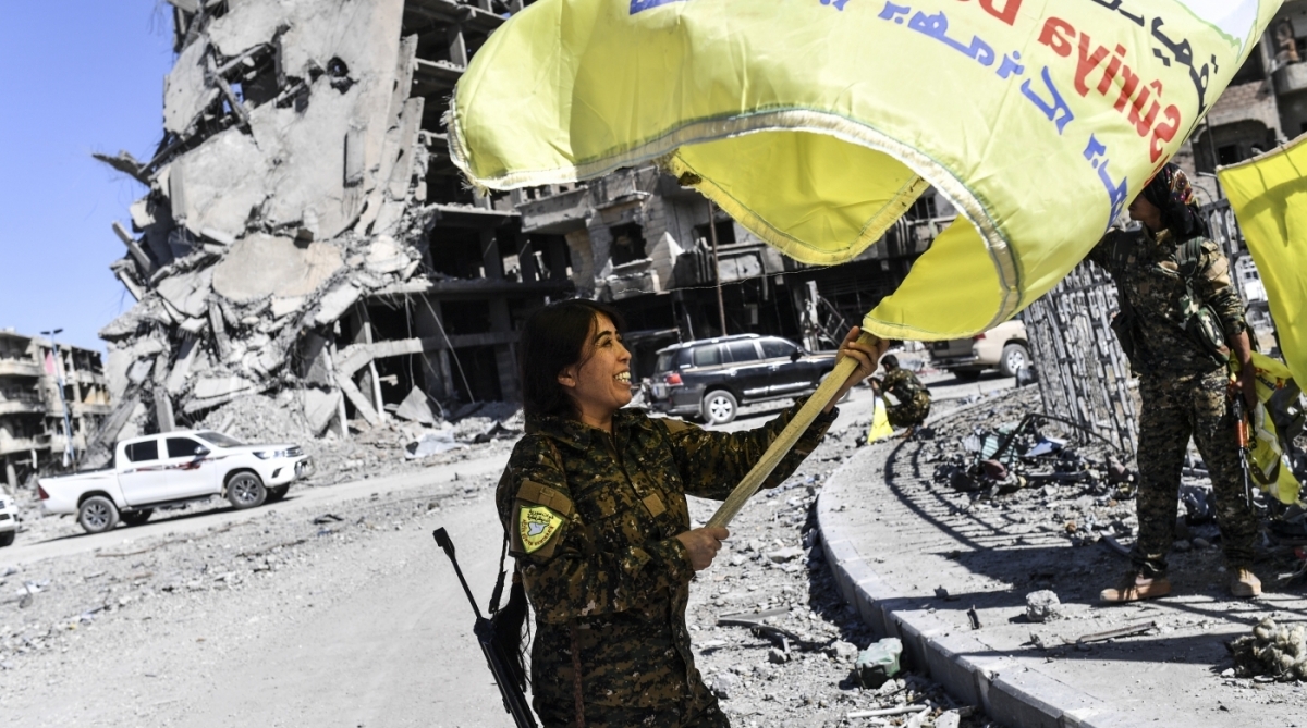 Rojda Felat, a Syrian Democratic Forces (SDF) commander, waves her group's flag at the iconic Al-Naim square in Raqa on October 17, 2017.
US-backed forces said they had taken full control of Raqa from the Islamic State group, defeating the last jihadist holdouts in the de facto Syrian capital of their now-shattered 