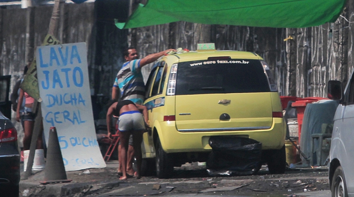 0-20-7--20 -  Flagrante- Taxista da cooperativa Ouro Taxi numero 048 &eacute; a flagrado lavando o carro no lava-jato clandestino da Mangueira, a placa tinha um saco preto para evitar a  multa. Rua Visconde de Niter&oacute;i, Mangueira.   Foto - Ma&iacute;ra Coelho / Ag&ecirc;ncia O Dia. Cidade, Crime, Multa, Irregularidade, Roubo, &aacute;gua, Comunidade, Desemprego,