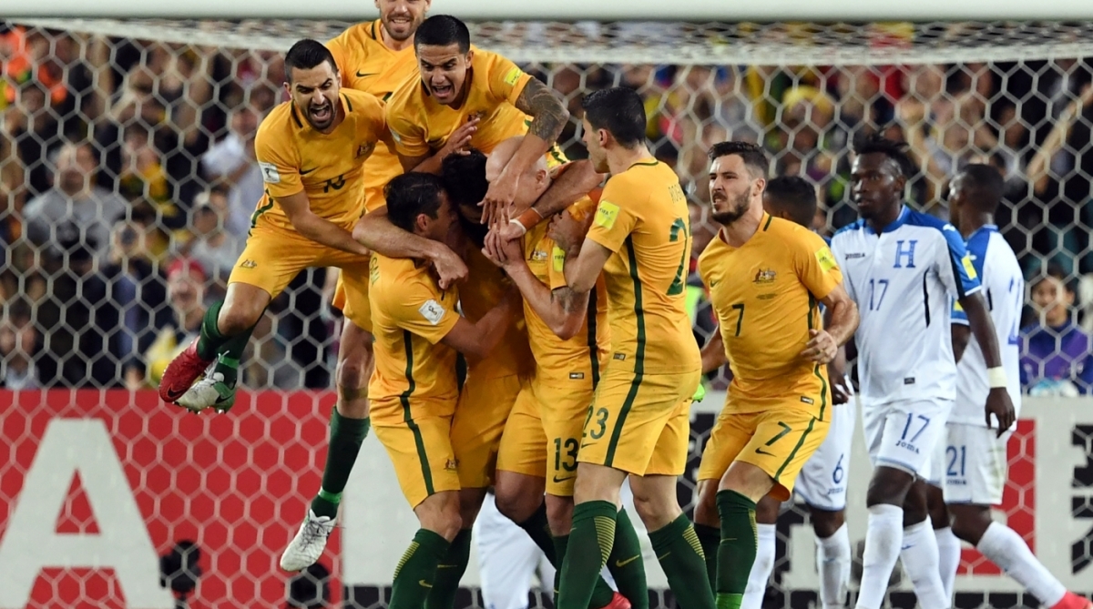 Australia's Mile Jedinak (C) is mobbed by his teammates after scoring against Honduras during their 2018 World Cup qualification play-off football match at Stadium Australia in Sydney on November 15, 2017. / AFP PHOTO / William WEST / -- IMAGE RESTRICTED TO EDITORIAL USE - STRICTLY NO COMMERCIAL USE --
      Caption - AFP