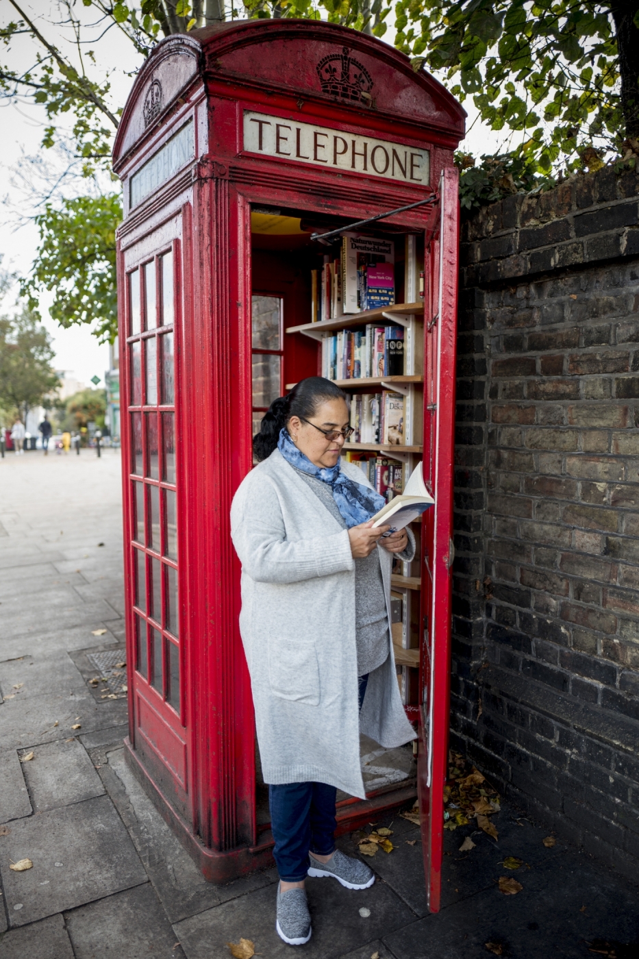 A pedestrian walks past a coffee shop run by Umar Khalid (unseen) in a red telephone box in Hampstead Heath, north London on October 20, 2017.
Facing extinction due to ubiquitous mobile phones, Britain's classic red telephone boxes are being saved from death row by ingenious conversions into all sorts of new uses. / AFP PHOTO / Tolga Akmen / TO GO WITH AFP STORY 'Britain-heritage-business' by Martine PAUWELS