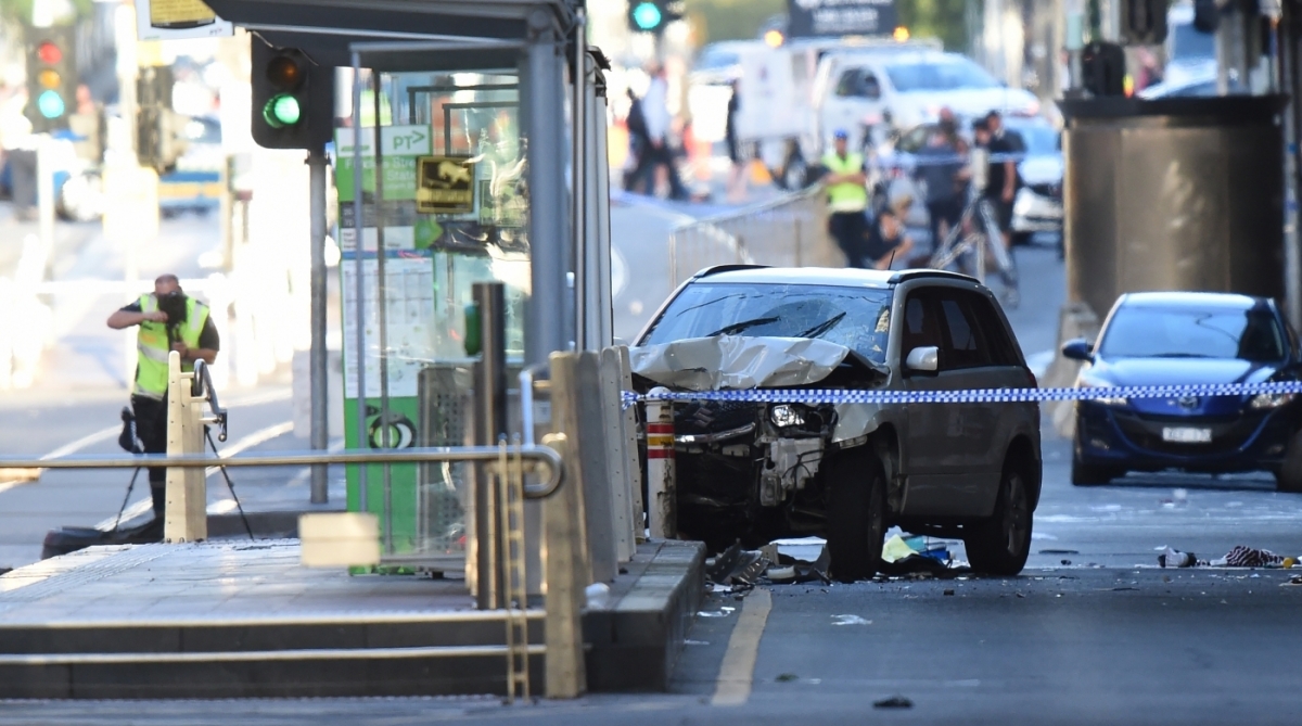 A white SUV (C) sits in the middle of the road as police and emergency personnel work at the scene of where a car ran over pedestrians in Flinders Street in Melbourne on December 21, 2017.
The car ploughed into a crowd in Australia's second-largest city on December 21 in what police said was a "deliberate act" that left more than a dozen people injured, some of them seriously. / AFP PHOTO / Mal Fairclough