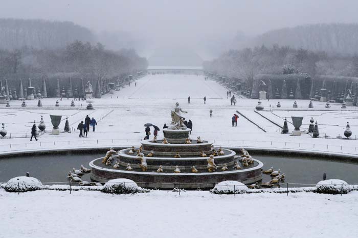 Pessoas andam sobre a neve que cobre o Palácio de Versailles, em Paris