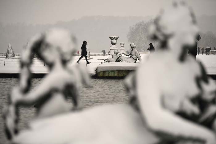 Pessoas atravessam os jardins do Palácio de Versailles cobertos pela neve