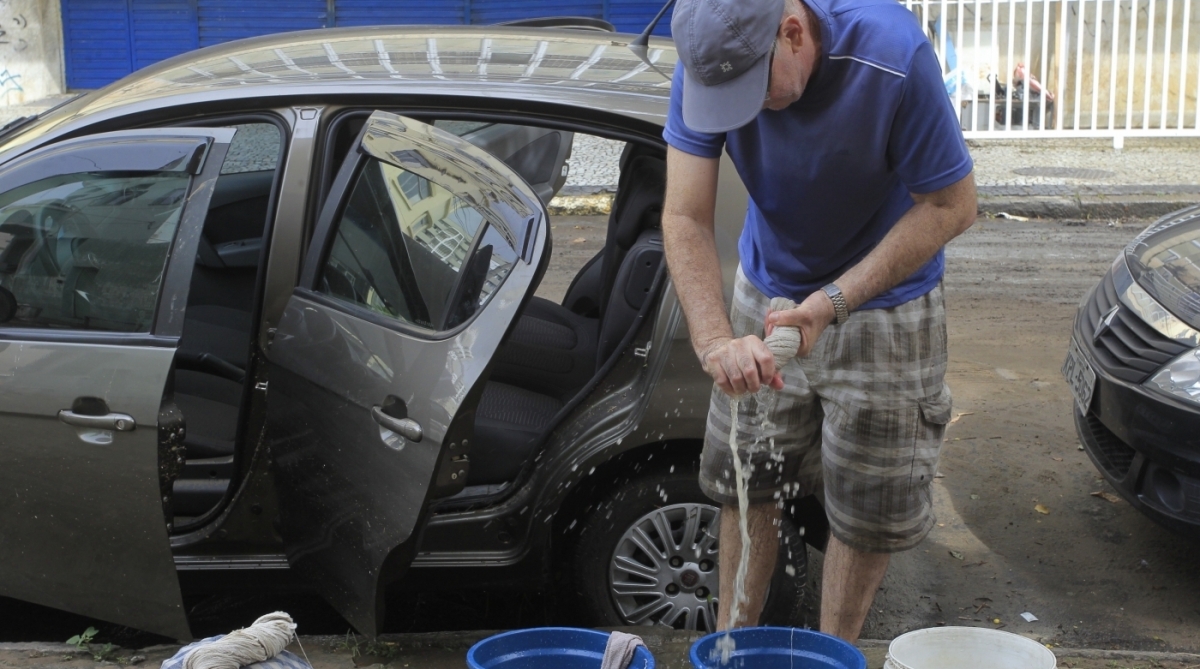 15/2/2018 - Comerciantes da Praça da Bandeira fazem mutirão para limpar suas lojas após o temporal. Com a mangueira, Izabel da Motta, dona da Loja. Foto de Maíra Coelho / Agência O Dia.
