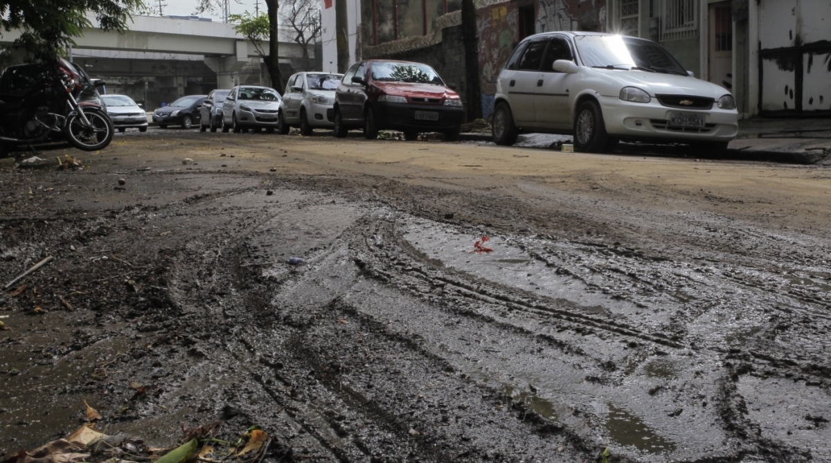 15/2/2018 - Comerciantes da Praça da Bandeira fazem mutirão para limpar suas lojas após o temporal. Com a mangueira, Izabel da Motta, dona da Loja.    Foto de Maíra Coelho / Agência O Dia. 