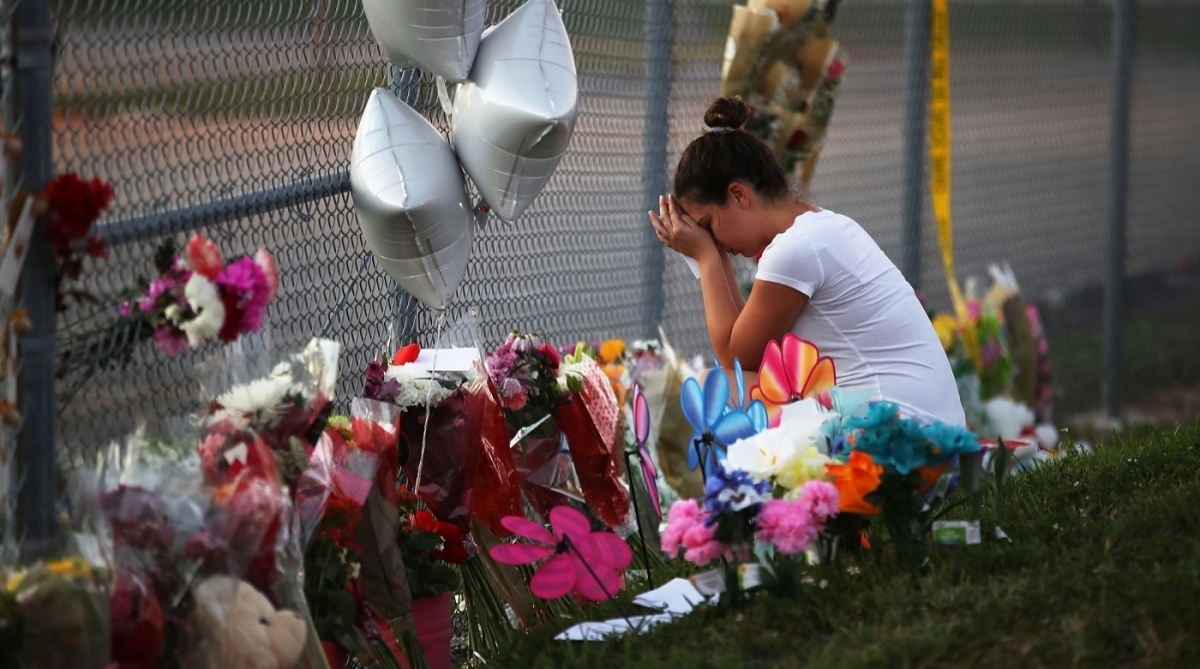 PARKLAND, FL - FEBRUARY 18: Shana Rosenthal, a student at Marjory Stoneman Douglas High School, visits a makeshift memorial setup in front of the school on February 18, 2018 in Parkland, Florida. Police arrested and charged 19 year old former student Nikolas Cruz for the February 14 shooting that killed 17 people.   Joe Raedle/Getty Images/AFP
      Caption