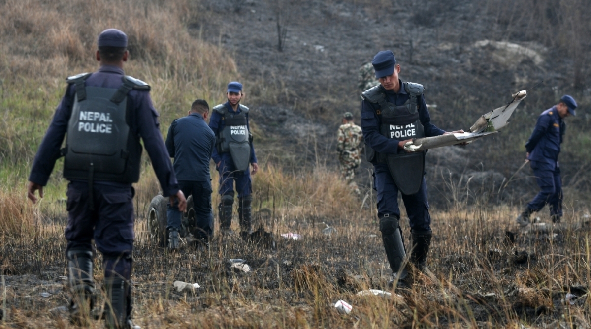 Agentes de resgate nepal&ecirc;s coletam os destro&ccedil;os de um avi&atilde;o que caiu perto do aeroporto internacional em Katmandu.