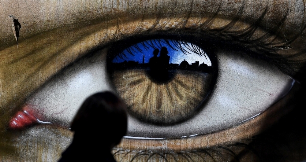 Em Roma, uma garota passa por uma obra pintada pelo artista de rua britnico My Dog Sighs, famoso por retratar olhos em lugares pblicos