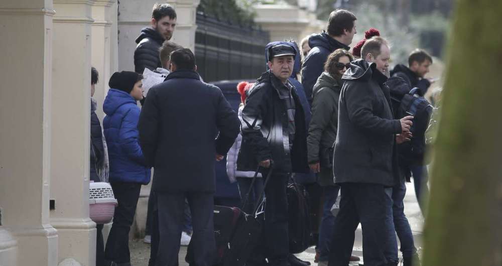 Pessoas carregam bagagens e deixam a embaixada russa em Londres. 