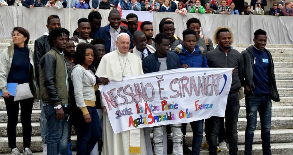 O papa Francisco posa com um grupo de migrantes na Praa So Pedro, no Vaticano. Na faixa, a mensagem:'ningum  estrangeiro'