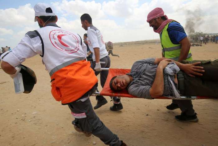 Os palestinos carregam um manifestante ferido durante confrontos com forças israelenses ao longo da fronteira com a Faixa de Gaza