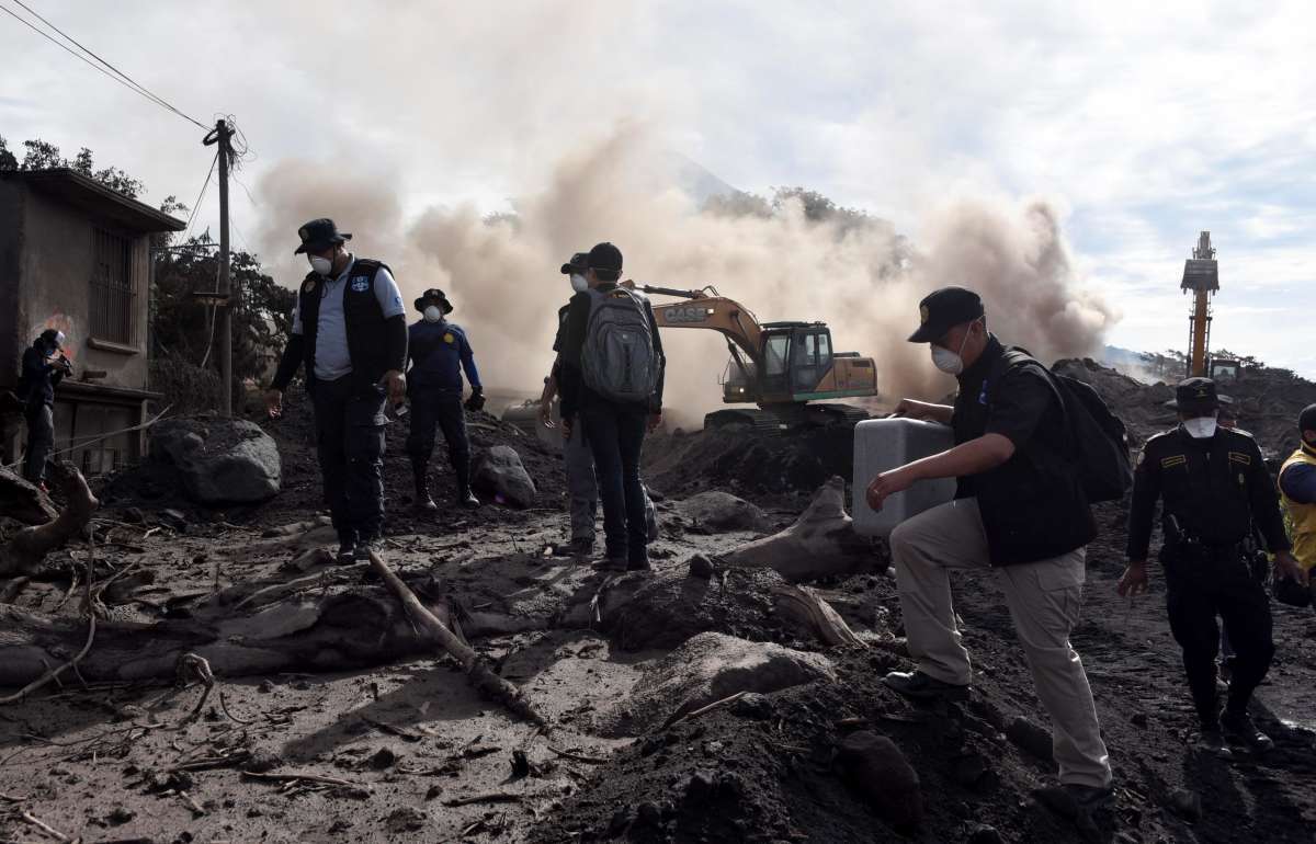 Policiais procuram por vítimas da erupção do Vulcão de Fogo na aldeia de San Miguel Los Lotes, coberta de cinzas, no departamento de Escuintla, a cerca de 35 km a sudoeste da Cidade da Guatemala - Johan Ordonez / AFP