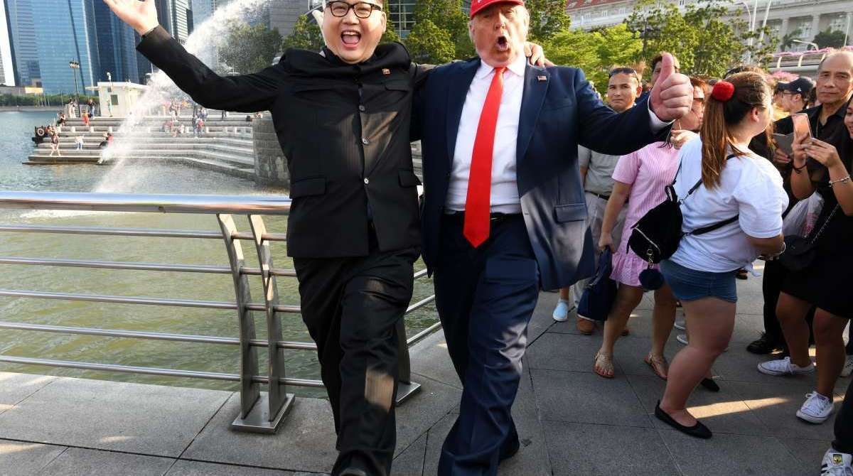 North Korean leader Kim Jong Un impersonator Howard X (L) and Donald Trump impersonator Dennis Alan (R) react at the Merlion park in Singapore on June 8, 2018. / AFP PHOTO / ROSLAN RAHMAN