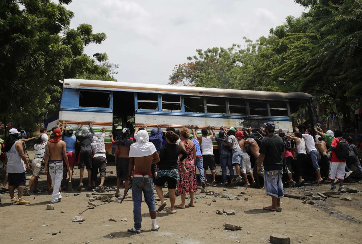 Demonstrators try to turn over a bus set alight during a day-long national strike held to mark two months of violent chaos under President Daniel Ortega, in Tipitapa, about 25 km from Managua on June 14, 2018
A national strike got underway Thursday in Nicaragua to protest the government's deadly crackdown on a two-month long popular uprising against Ortega, hours after the Church moved towards rekindling talks to calm the crisis rights groups say has killed at least 157 people. / AFP PHOTO / Inti OCON