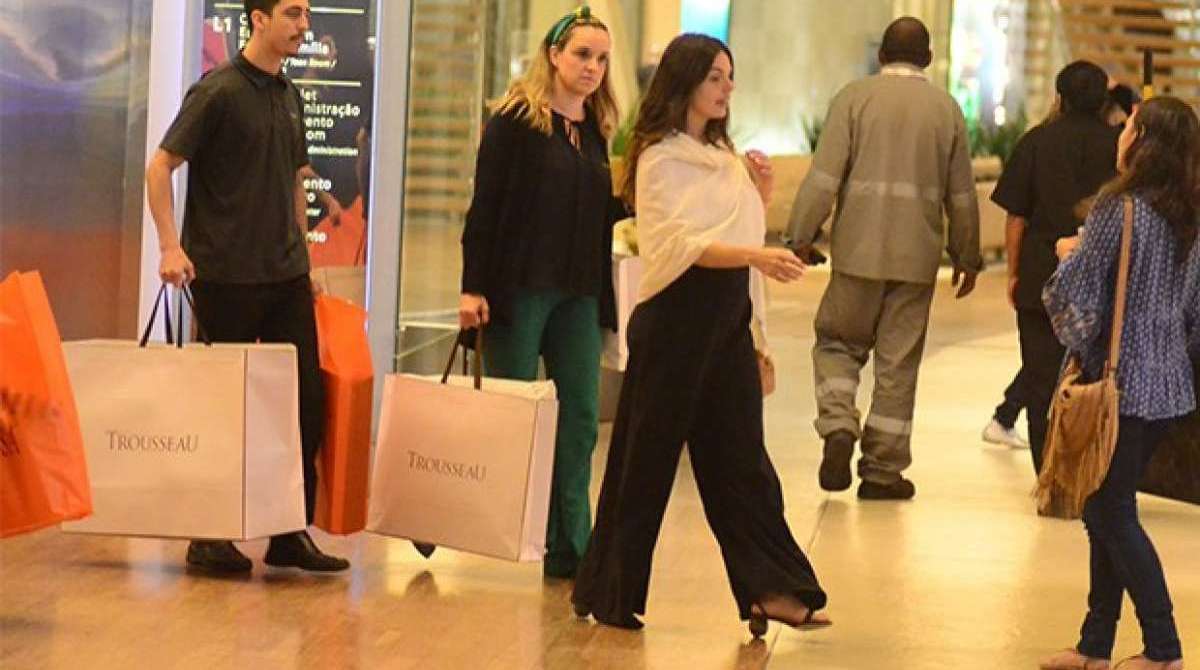 Grávida, Isis Valverde conta com ajuda para carregar suas compras. Atriz espalhou simpatia em shopping no Rio