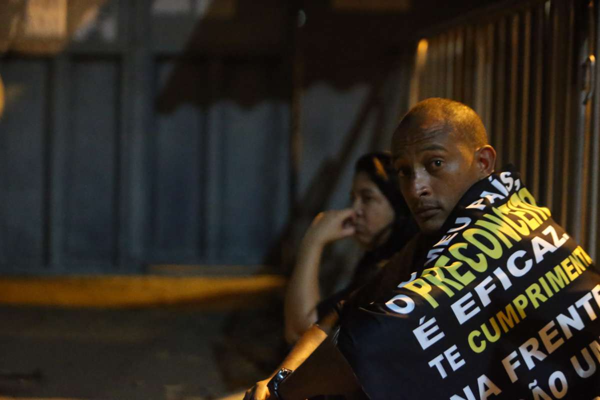 Antonio Carlos Rodrigues Junior, preso no lugar de um criminoso que roubou a c&ocirc;nsul-geral adjunta da Venezuela no Rio, aguarda a soltura do motorista que ficou sete dias detido na Cadeia de Benfica, na Zona Norte do Rio. O of&iacute;cio confirmando a soltura foi entregue somente na noite desta sexta-feira depois de dias de ang&uacute;stia para a fam&iacute;lia de Prw, como o homem &eacute; conhecido entre os amigos. Na foto Leonardo Ribeiro( irmao do preso) com uma bandeira com a foto do irmao e a esposa de preto e cabelo logo, Inggred Luna. Foto: Daniel Castelo Branco / Agencia O Dia