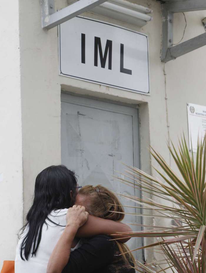 Luisa (de preto), m&atilde;e do MC G3, &eacute; amparada por parentes no IML