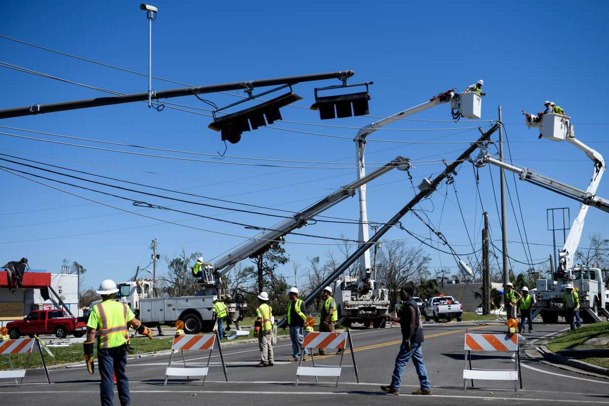 Utility workers repair power lines in the aftermath of Hurricane Michael in Panama City, Florida on October 12, 2018. - Rescue teams using sniffer dogs carried out a grim search for victims of Hurricane Michael on Friday amid fears that the death toll from the monster storm, which currently stands at 11, could rise. (Photo by Brendan Smialowski / AFP)
      Caption