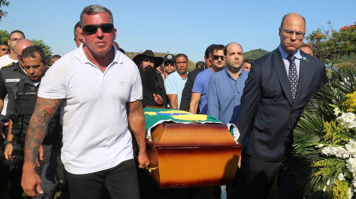 O governador Wilson Witzel (à direita) ajuda a carregar, no domingo, o caixão com o corpo do PM Daniel Henrique Mariotti, morto na véspera