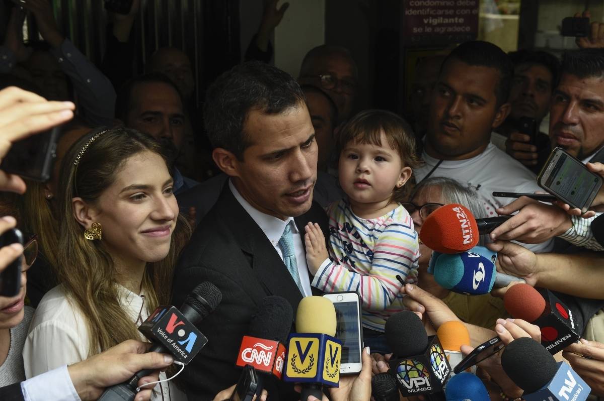 Líder opositor e autoproclamado presidente da Venezuela, Juan Guaidó fala à imprensa com filha no colo e ao lado da mulher, Fabiana Rosales, em frente à sua casa - Fredericao Parra/ AFP