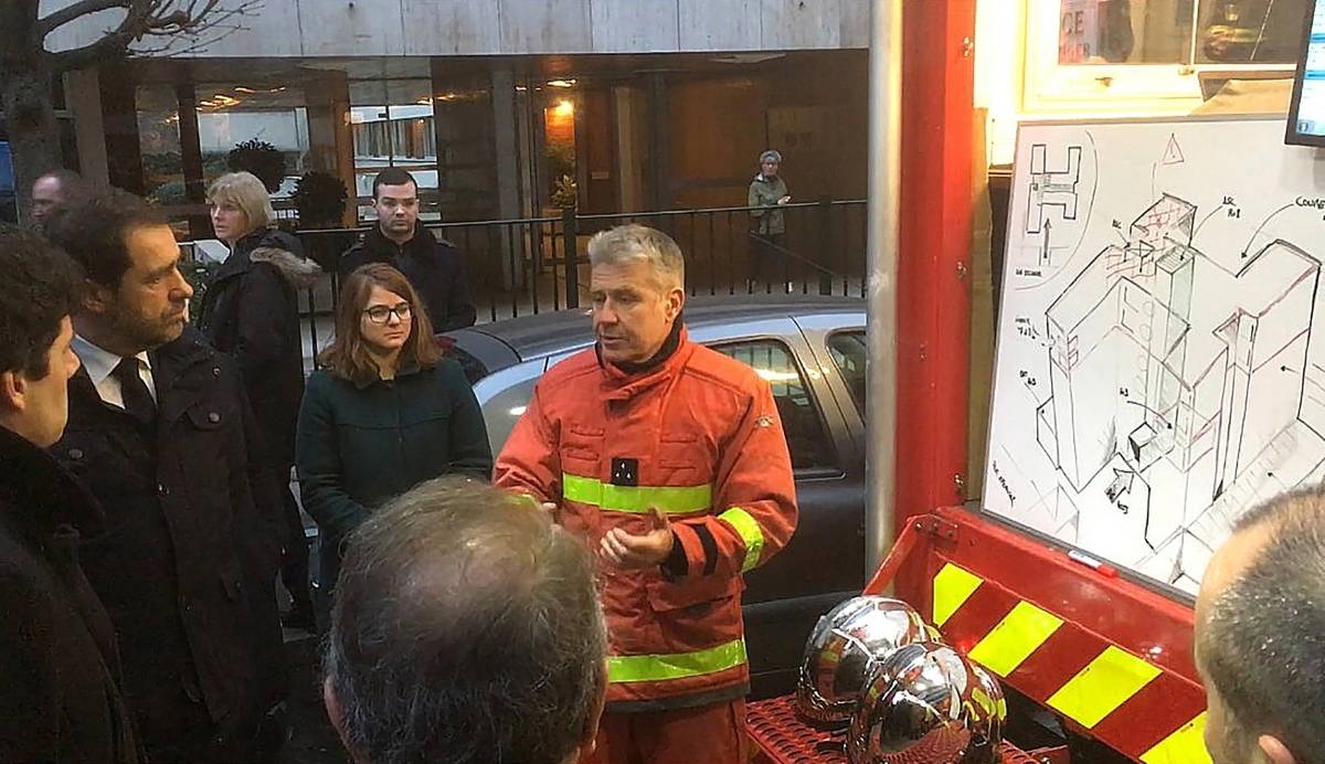 O ministro do Interior da França, Christophe Castaner, ouve um bombeiro falando em frente ao prédio onde um incêndio matou 8 pessoas