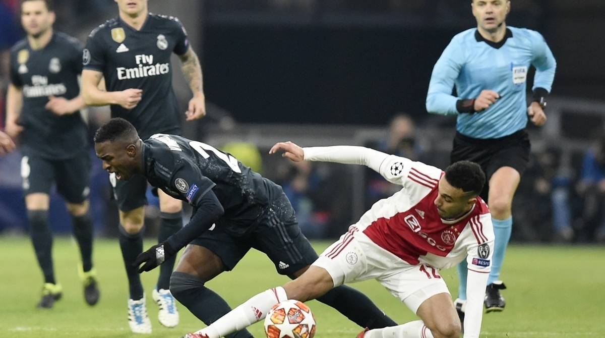 Real Madrid's Brazilian forward Vinicius Junior (L) fights for the ball with Ajax's Dutch defender Noussair Mazraoui during the UEFA Champions league round of 16 first leg football match between Ajax Amsterdam and Real Madrid at the Johan Cruijff ArenA on February 13, 2019. (Photo by JOHN THYS / AFP)