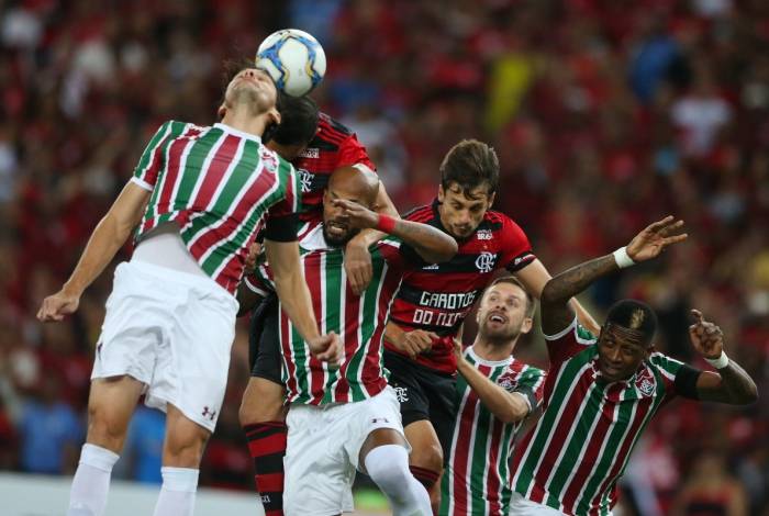 Matheus Ferraz (E) tenta tirar o perigo da área do Fluminense
