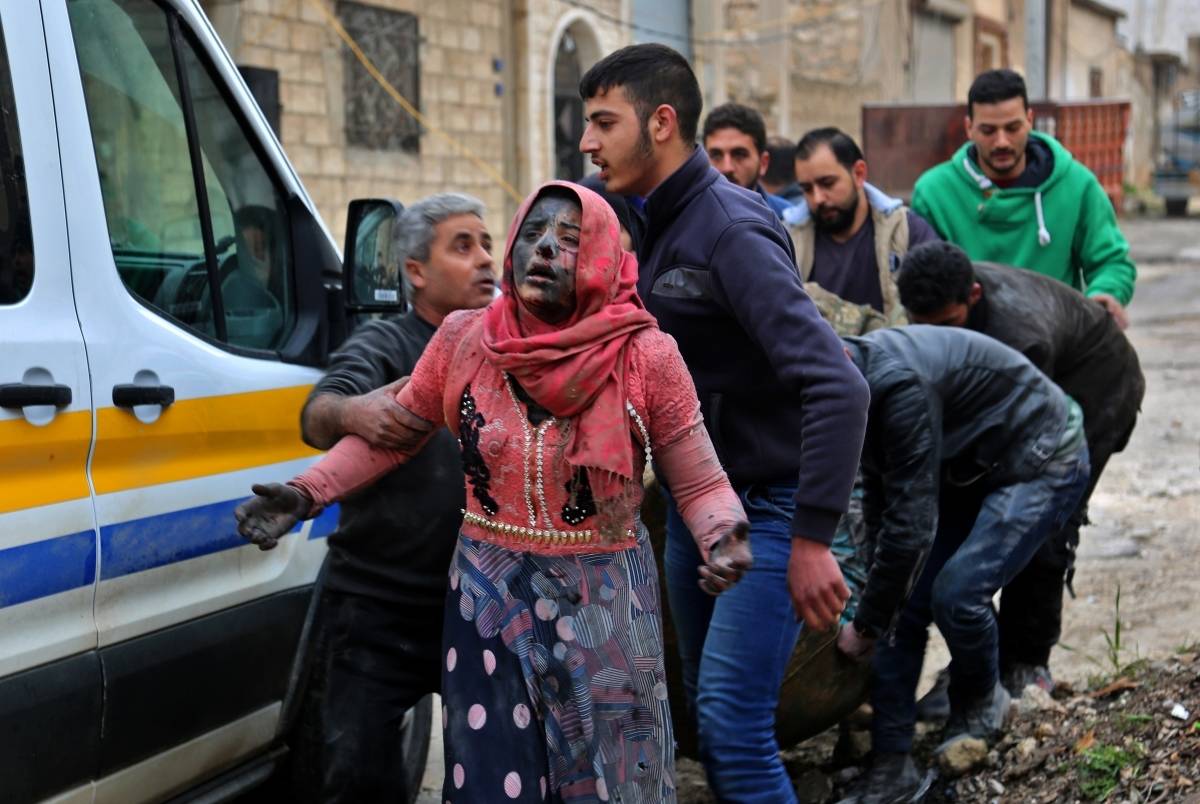 Homem sírio ajudando mulher ferida após bombardeio na cidade de Khan Shaykhun in no sudeste do Paquistão