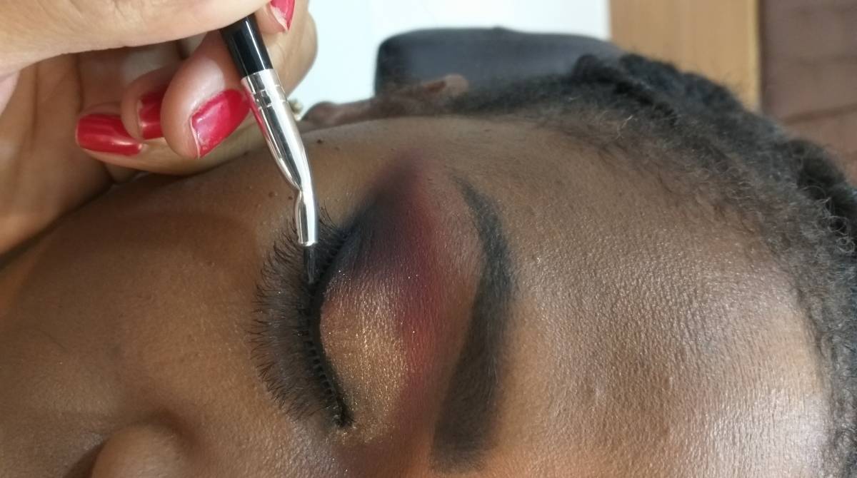 Ilumine abaixo das sobrancelhas para dar vida a região. Depois, é a vez da pele. Misture vários tons de base marrom, para achar o tom exato da pele e espalhe-os até ficar uniforme. Sele com pó compacto