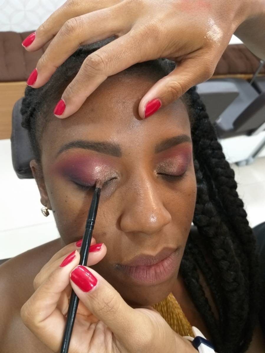 O passo seguinte é desenhar as sobrancelhas com sombra marrom. Após passar sombra laranja e um pouquinho de preto no canto externo. No canto interno, use um iluminador com um pouquinho de glitter dourado