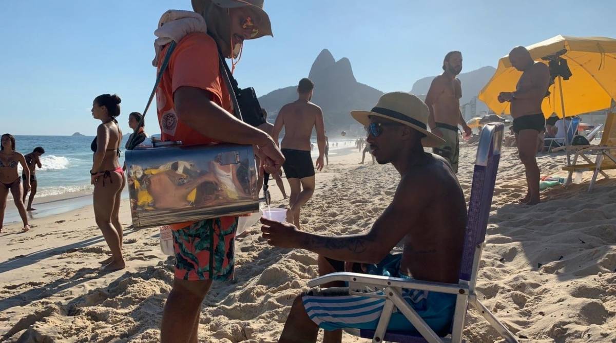 Vendedor usa caixa de som presa ao seu pescoço para divulgar seu trabalho nas areias de Ipanema