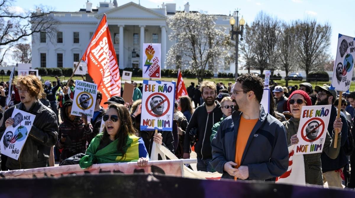 American and Brazilian activists protest against the upcoming visit of Brazilian President Jair Bolsonaro,  March 17, 2019 on Lafayette Square before the White House (background) in Washington, DC. - The far-right leader Bolsonaro departed for Washington March 17, 2019 to meet with his US counterpart Donald Trump and cement a budding conservative-populist alliance that, in part, aims to ramp up pressure on Venezuela. (Photo by Eric BARADAT / AFP)