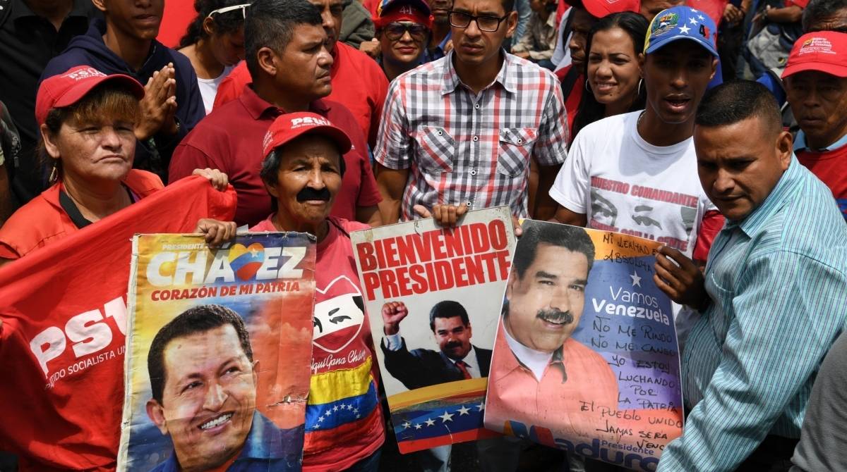 Apoiadores do presidente venezuelano, Nicolas Maduro, exibem um cartaz com fotos de Maduro e do falecido líder Hugo Chávez durante uma manifestação
