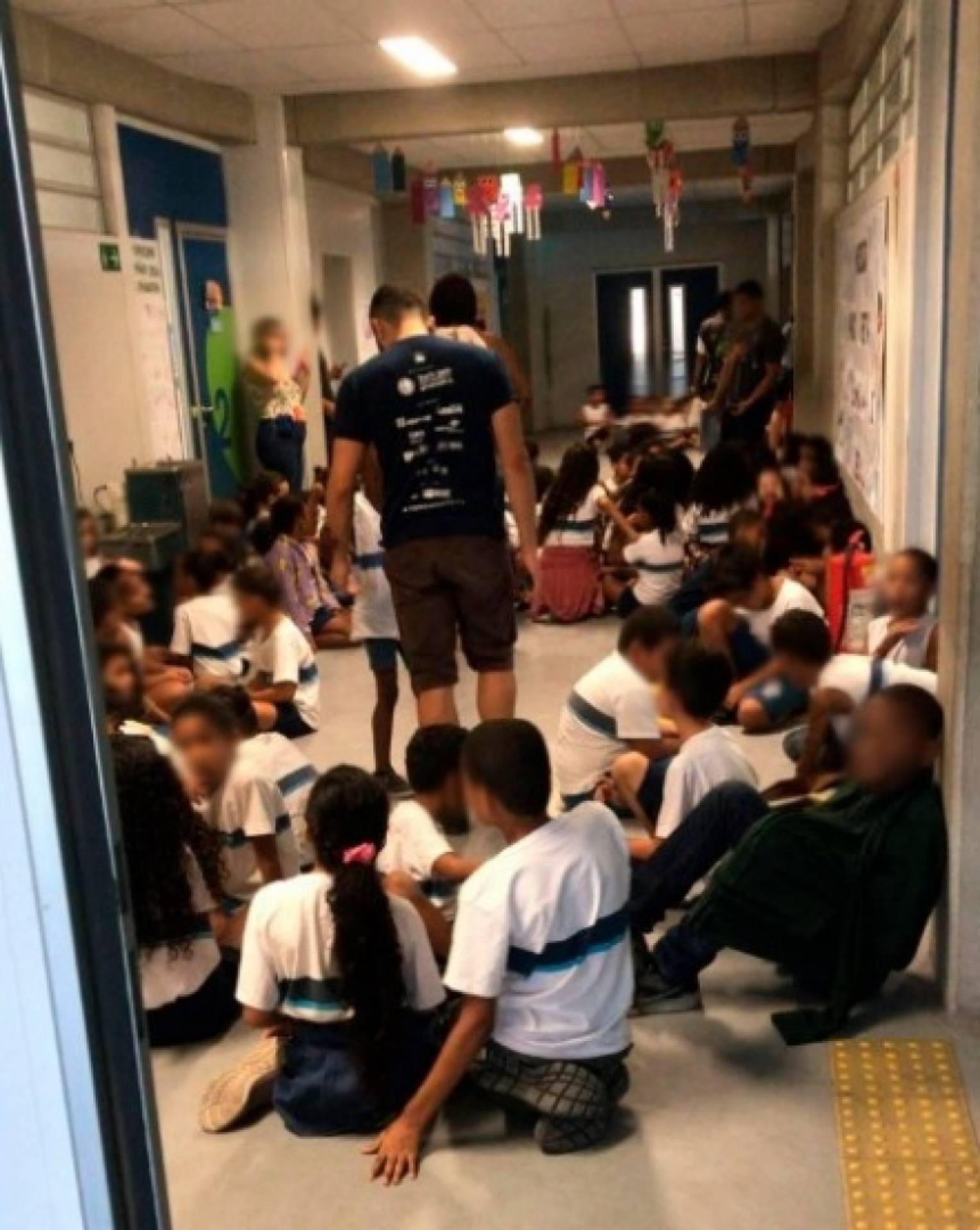 Crianças se protegem no corredor da escola
