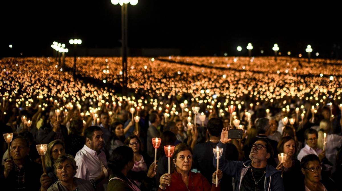 Peregrinos seguram velas enquanto rezam durante a procissão de velas no santuário de Fátima, em Fátima, no centro de Portugal, em 12 de maio de 2019
