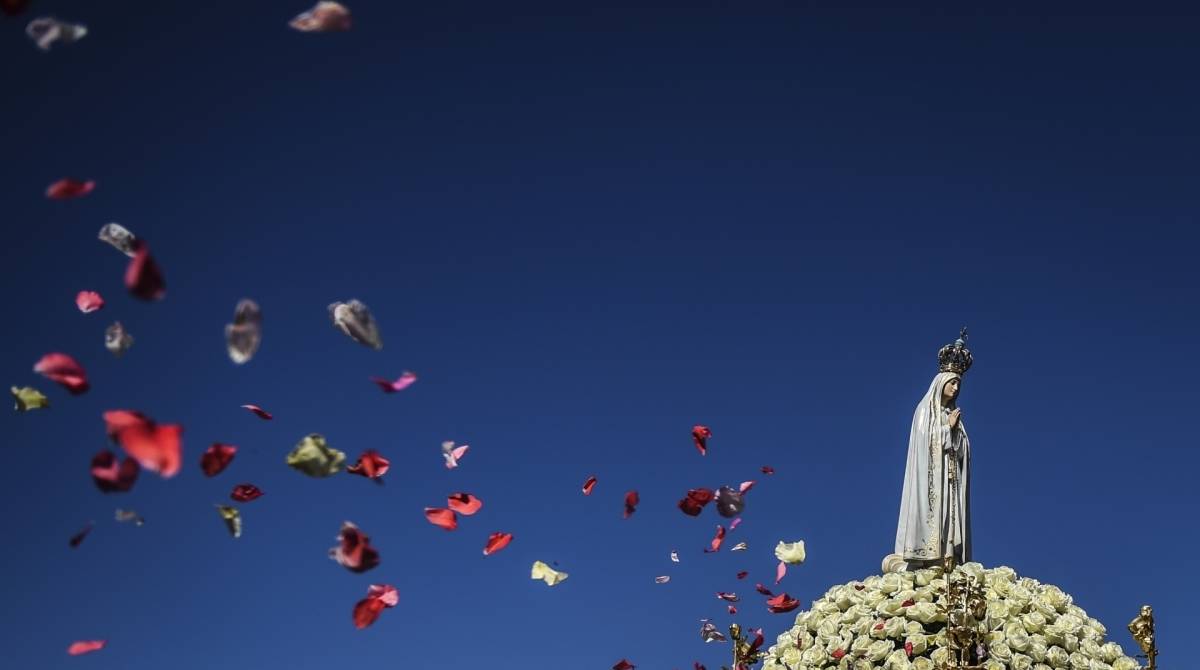 As pessoas jogam pétalas de rosas na imagem de Nossa Senhora Fátima durante uma procissão no Santuário de Fátima, em Fátima, no centro de Portugal