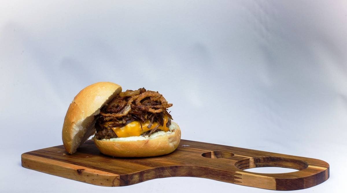 Mokaie Smoked Rib Burger, blend de fraldinha e peito bovino, costela bovina defumada, cheddar, cebola, maionese de alho e pão