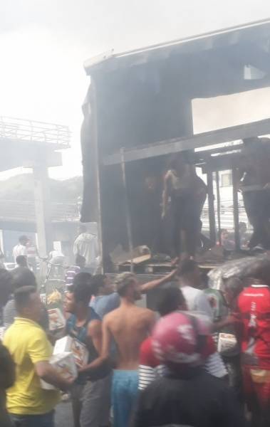 Pessoas entram em caminhão em chamas para retirar carga de cerveja