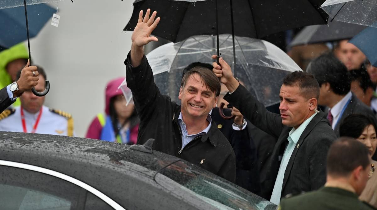 Presidente Jair Bolsonaro acena ao chegar ao aeroporto de Kansai, antes da cúpula do G20 em Osaka - Charly Triballeau/ AFP
