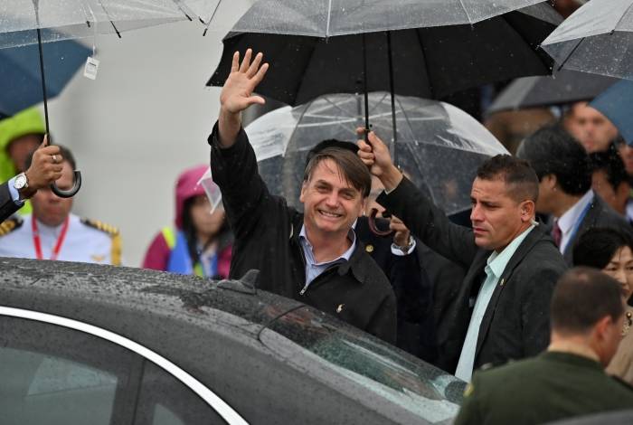 Presidente Jair Bolsonaro acena ao chegar ao aeroporto de Kansai, antes da cúpula do G20 em Osaka