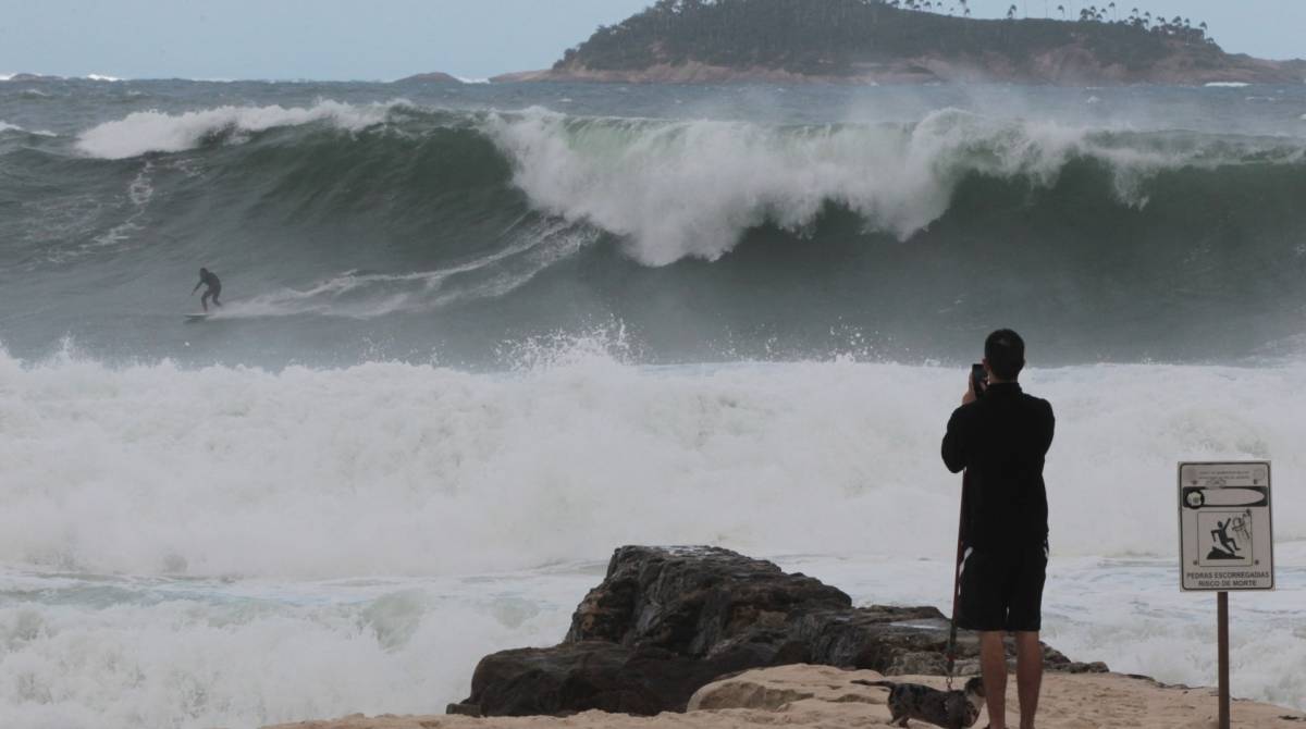 Cariocas e turistas aproveitam o fim de semana na praia mesmo com muito frio e chuva. Na foto, surfista no Leblon.  