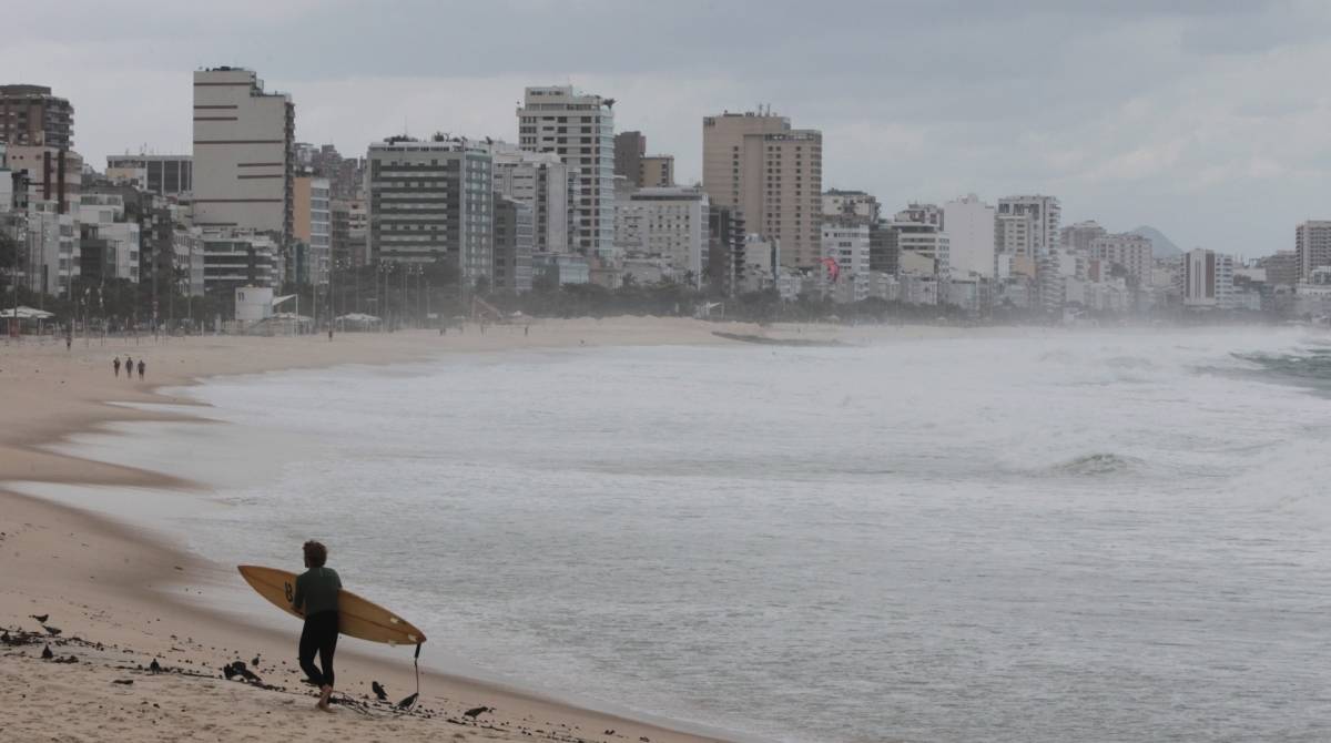 Cariocas e turistas aproveitam o fim de semana na praia mesmo com muito frio e chuva. Na foto, surfista no Leblon.   