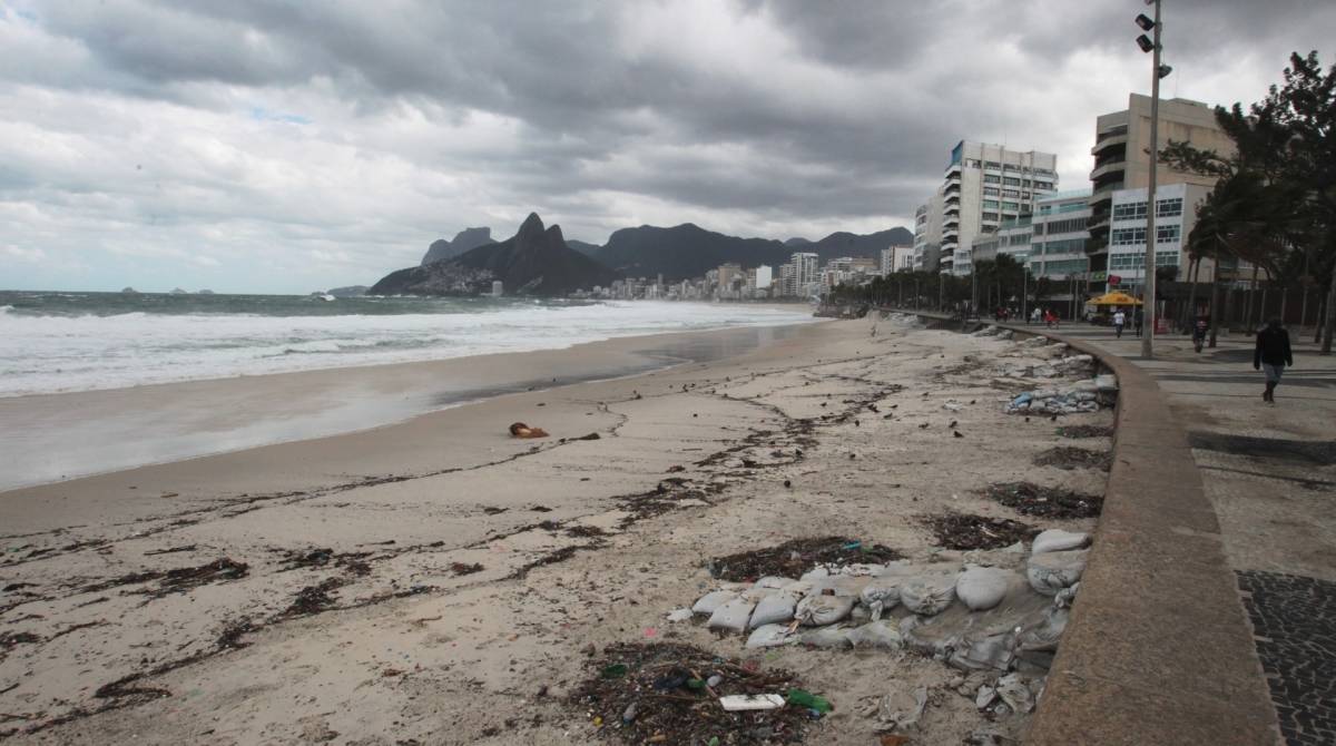 Cariocas e turistas aproveitam o fim de semana na praia mesmo com muito frio e chuva. Na foto, ressaca leva detritos e muita areia para o Arpoador.   