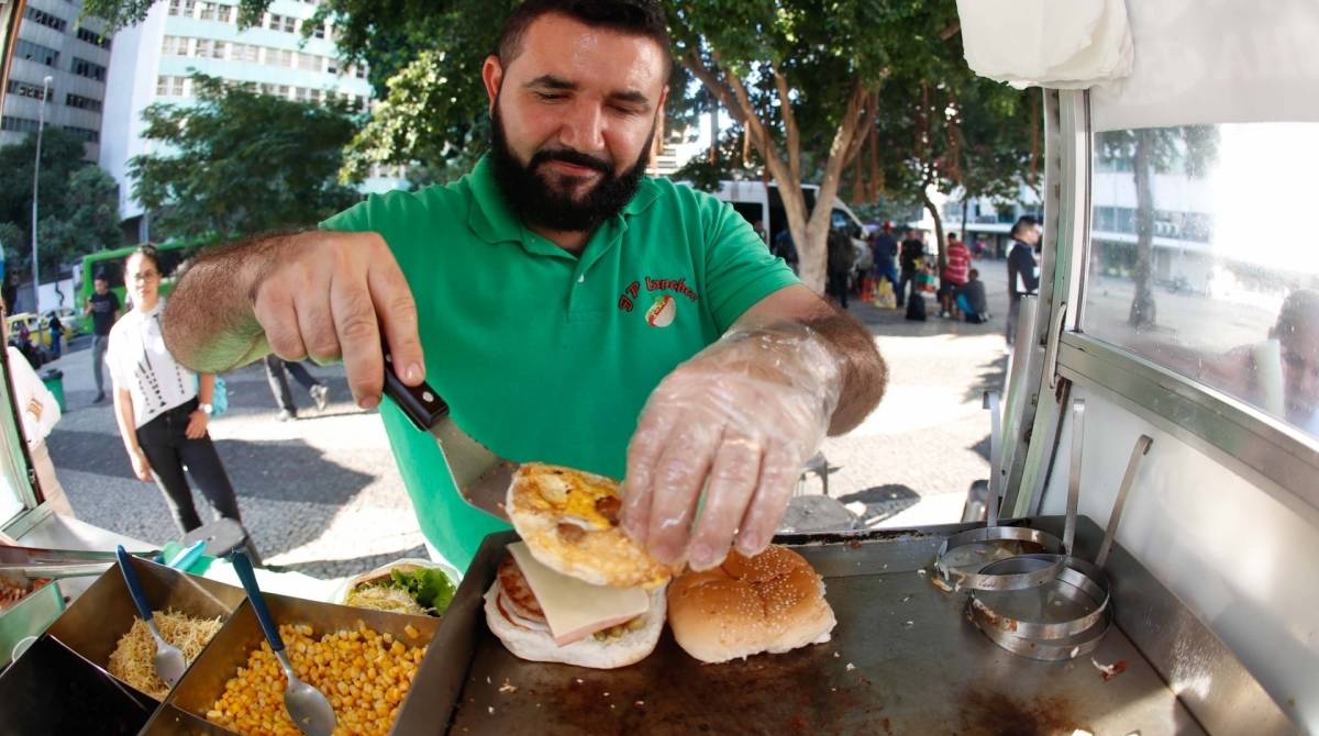 No Largo da Carioca, João Paulo frita cerca de 100 hambúrgueres por dia. Rotina puxada: 'fico em pé o dia inteiro. À noite, as pernas doem'. - fotos de Gilvan de Souza