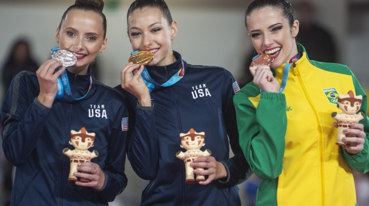 US Evita Griskenas (C), US Camilla Feeley (L) and Brazil's Natalia Gaudio pose in the podium of the Individual All Around of the Rhythmic Gimnastics competition during the Lima 2019 Pan-American Games in Lima on August 3, 2019. (Photo by ERNESTO BENAVIDES / AFP)