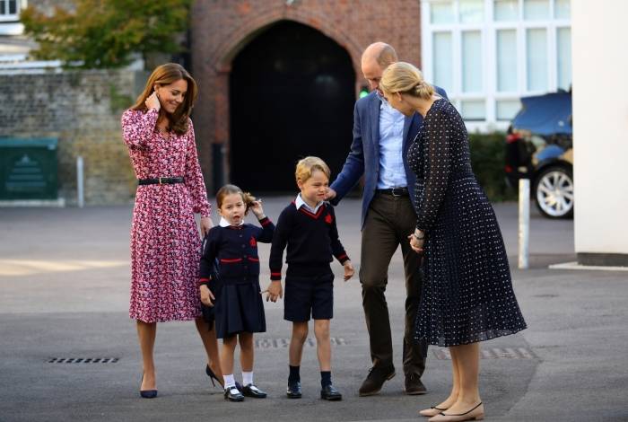 A princesa Charlotte de Cambridge e seu irmão, príncipe George de Cambridge, são recebidos por Helen Haslem, diretora da escola  - Aaron Chown / Pool/ AFP