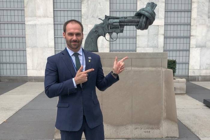 Eduardo Bolsonaro posa com arminha em frente à escultura contra a violência na ONU