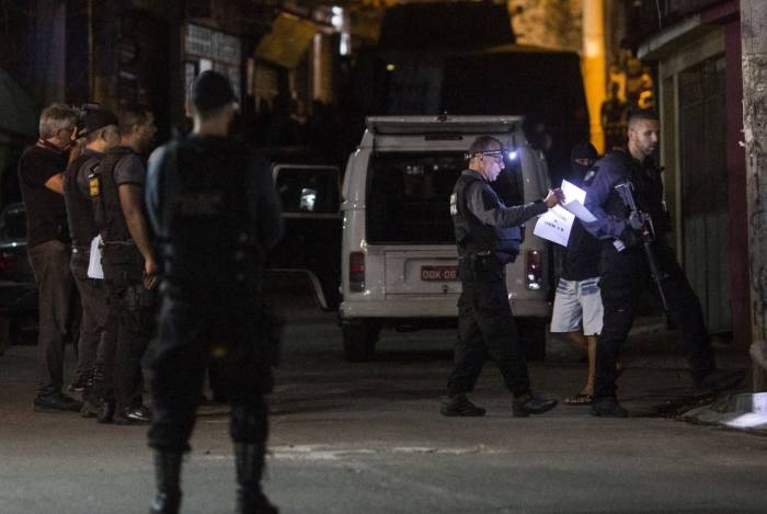 A witness (C masked) speaks with Brazilian policemen during the reconstruction of the murder of eight-year-old Agatha Sales Felix, at Alemao Favelas complex, Rio de Janeiro, Brazil, on October 01, 2019. - Felix died during a confrontation between alleged drug traffickers and police officers on September 21. (Photo by Daniel RAMALHO / AFP)